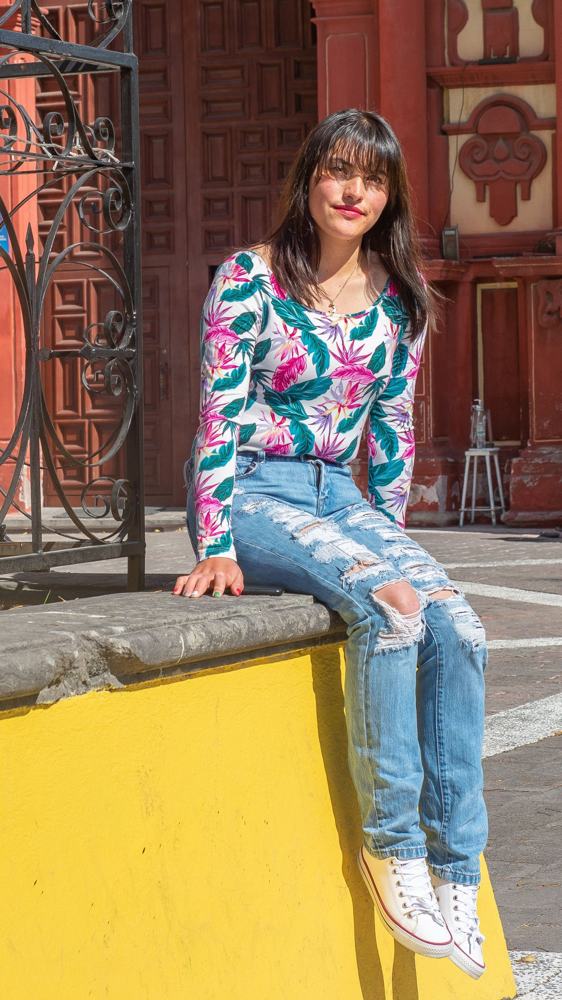 Mujer joven sentada frente a una iglesia colonial