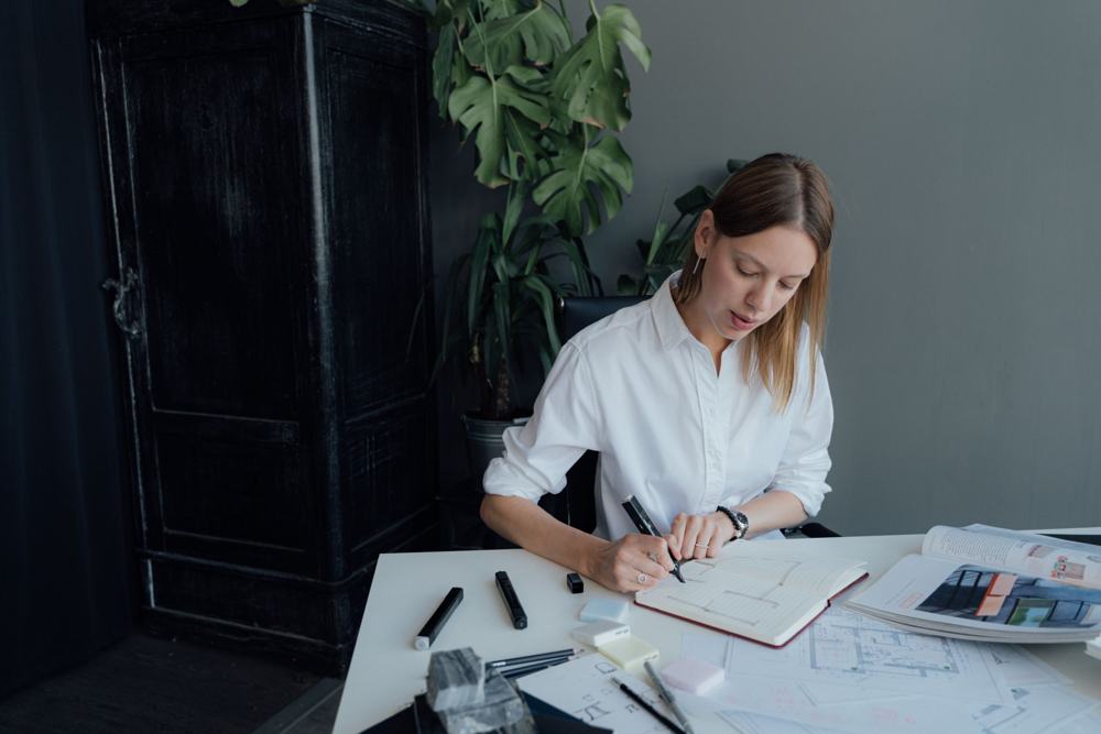 Mujer trabajando en su escritorio con planos y libreta